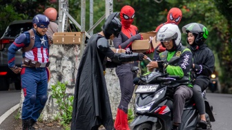 Anggota Komunitas Badut Cimahi mengenakan kostum superhero saat membagikan takjil kepada pengendara di Kota Cimahi, Jawa Barat, Senin (23/2/2026). [ANTARA FOTO/Abdan Syakura/rwa]