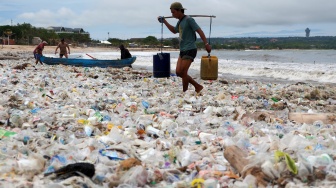 Nelayan mengangkut air melewati tumpukan sampah kiriman di Pantai Kedonganan, Badung, Bali, Kamis (26/2/2026). [ANTARA FOTO/Nyoman Hendra Wibowo/rwa]