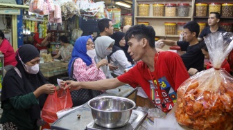 Pedagang melayani pembeli kue kering yang dijual di Pasar Jatinegara, Jakarta, Senin (9/3/2026). [Suara.com/Alfian Winanto]