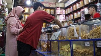 Pedagang melayani pembeli kue kering yang dijual di Pasar Jatinegara, Jakarta, Senin (9/3/2026). [Suara.com/Alfian Winanto]