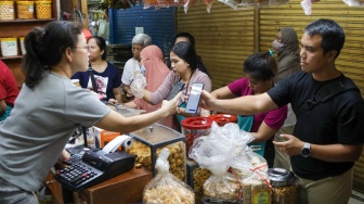 Pedagang melayani pembeli kue kering yang dijual di Pasar Jatinegara, Jakarta, Senin (9/3/2026). [Suara.com/Alfian Winanto]