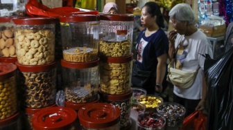 Pedagang melayani pembeli kue kering yang dijual di Pasar Jatinegara, Jakarta, Senin (9/3/2026). [Suara.com/Alfian Winanto]