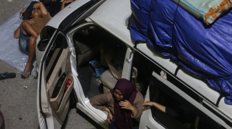 Pemudik tidur di depan kendaraannya saat antre memasuki kapal di Pelabuhan Merak, Kota Cilegon, Banten, Rabu (18/3/2026). [ANTARA FOTO/Angga Budhiyanto/foc]
