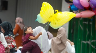 Seorang anak memegang balon saat akan melaksanakan Salat Idul Fitri 1447 Hijriah di Jatinegara, Jakarta, Jumat (21/3/2026). [Suara.com/Alfian Winanto]