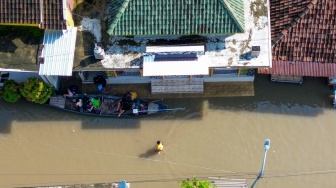 Foto udara warga berjalan dan menggunakan perahu saat banjir di Desa Kedungringin, Beji, Pasuruan, Jawa Timur, Rabu (25/3/2026). [ANTARA FOTO/Umarul Faruq/tom]
