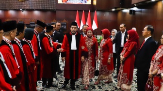 Hakim Konstitusi Anwar Usman berjalan ke depan gedung saat acara Wisuda Purnabakti dan Penyambutan Hakim di Gedung Mahkamah Konstitusi, Jakarta, Senin (13/4/2026). [Suara.com/Alfian Winanto]