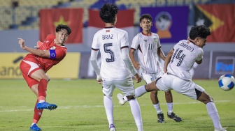 Pesepak bola Timnas Indonesia Putu Ekayana (kiri) menendang bola dan berusaha dihalau pesepak bola Timor Leste Florindo De Araujo (kanan) pada pertandingan penyisihan grup A ASEAN U-17 Boys Championship atau AFF U-17 di Stadion Gelora Joko Samudro, Gresik, Jawa Timur, Senin (13/4/2026). [ANTARA FOTO/Rizal Hanafi/sgd]