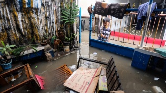 Seorang anak menutup pintu gerbang rumahnya yang terendam banjir di Kampung Gambiran, Kabupaten Sukoharjo, Jawa Tengah, Rabu (15/4/2026). [ANTARAFOTO/Maulana Surya/YU]