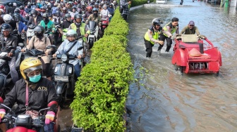 Polisi membantu pengemudi becak yang menghindari kemacetan akibat banjir di Jalan Yos Sudarso, perbatasan Kota Solo dan Kabupaten Sukoharjo, Jawa Tengah, Rabu (15/4/2026). [ANTARAFOTO/Maulana Surya/YU]
