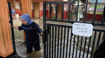 Seorang guru menutup gerbang sekolah yang terdampak banjir di SD Negeri Sanggrahan 01, Kabupaten Sukoharjo, Jawa Tengah, Rabu (15/4/2026). [ANTARAFOTO/Maulana Surya/YU]