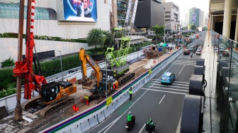 Kendaraan melintas di jalan yang menyempit dampak adanya pengerjaan proyek revitalisasi di Jalan M.H. Thamrin, Jakarta, Senin (20/4/2026). [Suara.com/Alfian Winanto]