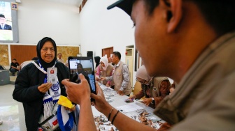 Petugas mendokumentasikan jemaah calon haji yang mulai memadati Embarkasi Haji Pondok Gede, Jakarta, Selasa (21/4/2026). [Suara.com/Alfian Winanto]
