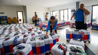 Petugas menyusun koper calon jamaah haji yang memasuki Asrama Haji Pondok Gede, Jakarta, Selasa (21/4/2026). [Suara.com/Alfian Winanto]
