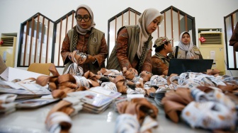 Petugas menyusun tag jemaah calon haji yang mulai memadati Embarkasi Haji Pondok Gede, Jakarta, Selasa (21/4/2026). [Suara.com/Alfian Winanto]
