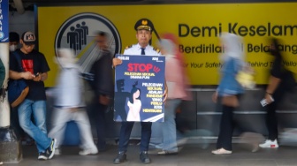 Petugas membawa poster kampanye anti kekerasan seksual di Stasiun Sudirman, Jakarta, Selasa (21/4/2026). [Suara.com/Alfian Winanto]
