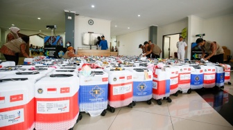 Petugas menyusun koper calon jamaah haji yang memasuki Asrama Haji Pondok Gede, Jakarta, Selasa (21/4/2026). [Suara.com/Alfian Winanto]
