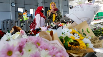 Warga berdoa di depan karangan bunga yang diletakkan di salah satu sudut Stasiun Bekasi Timur, Bekasi, Jawa Barat, Kamis (30/4/2026). [Suara.com/Alfian Winanto]
