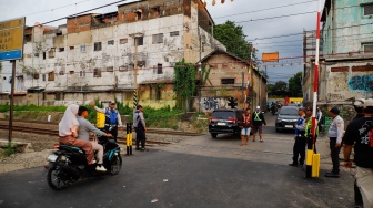 Pengendara melintasi rel perlintasan kereta api di dekat Stasiun Bekasi Timur, Bekasi, Jawa Barat, Rabu (30/4/2026). [Suara.com/Alfian Winanto]
