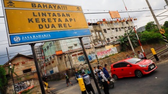 Pengendara melintasi rel perlintasan kereta api di dekat Stasiun Bekasi Timur, Bekasi, Jawa Barat, Rabu (30/4/2026). [Suara.com/Alfian Winanto]
