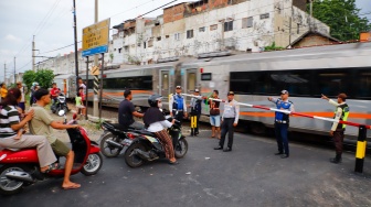Pengendara berhentinsaat kereta melintas di perlintasan kereta api di dekat Stasiun Bekasi Timur, Bekasi, Jawa Barat, Rabu (30/4/2026). [Suara.com/Alfian Winanto]
