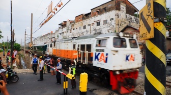 Pengendara berhentinsaat kereta melintas di perlintasan kereta api di dekat Stasiun Bekasi Timur, Bekasi, Jawa Barat, Rabu (30/4/2026). [Suara.com/Alfian Winanto]
