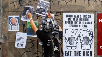 Massa dari berbagai elemen masyarakat dan buruh menempelkan poster pada aksi memperingati Hari Buruh Internasional atau May Day 2026 di depan gedung DPR RI, Jakarta, Jumat (1/5/2026). [Suara.com/Alfian Winanto]
