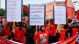 Massa dari berbagai elemen masyarakat dan buruh menempelkan poster pada aksi memperingati Hari Buruh Internasional atau May Day 2026 di depan gedung DPR RI, Jakarta, Jumat (1/5/2026). [Suara.com/Alfian Winanto]
