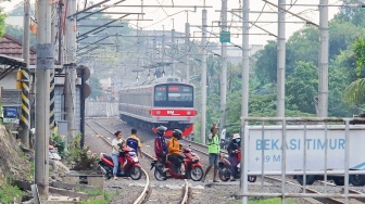 Pengendara melintasi rel perlintasan kereta api di dekat Stasiun Bekasi Timur, Bekasi, Jawa Barat, Rabu (30/4/2026). [Suara.com/Alfian Winanto]
