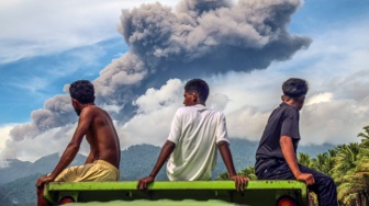 Warga melihat abu vulkanik keluar dari Gunung Dukono yang terlihat di area bekas banjir lahar dingin Desa Mamuya, Kecamatan Galela, Maluku Utara, Selasa (12/5/2026). [ANTARA FOTO/Andri Saputra/sgd]