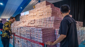 Petugas memasang garis penghalang pada tumpukan uang saat kegiatan penyerahan denda administratif dan lahan kawasan hutan di Kejaksaan Agung, Jakarta, Rabu (13/5/2026). [ANTARA FOTO/Bayu Pratama S/tom]