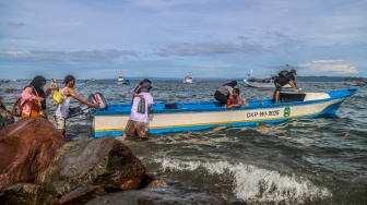 Warga naik ke dalam perahu motor yang bersandar di tepi bebatuan Pantai Labuha, Pulau Bacan, Kabupaten Halmahera Selatan, Maluku Utara, Selasa (26/5/2026). [ANTARA FOTO/Andri Saputra/agr]
