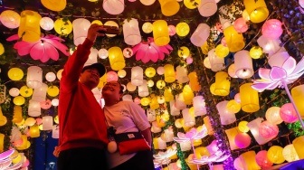 Warga berswafoto dengan ornamen lampu hias saat llumination of Jakarta: Glow of Peace di kawasan Bundaran HI, Jakarta, Jumat (29/5/2026). [Suara.com/Alfian Winanto]