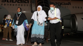 Petugas membantu jamaah haji kelompok terbang (kloter) pertama saat tiba di Bandara Internasional Juanda, Sidoarjo, Jawa Timur, Senin (1/6/2026). [ANTARA FOTO/Umarul Faruq/kye]