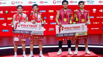 Pebulu tangkis ganda putra Indonesia Raymond Indra/Nikolaus Joaquin (kiri) dan ganda putra Malaysia Goh Sze Fei/Nur Izzuddin (kanan) berpose dengan pialanya usai pertandingan final Polytron Indonesia Open 2026 di Istora Senayan, Jakarta, Minggu (7/6/2026). [Suara.com/Alfian Winanto]
