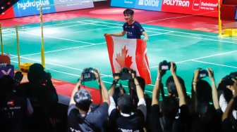 Pebulu tangkis tunggal putra Kanada Victor Lai berpose dengan bendera negaranya usai mengalahkan tunggal putra Indonesia Jonatan Christie pada final Polytron Indonesia Open 2026 di Istora Senayan, Jakarta, Minggu (7/6/2026). [Suara.com/Alfian Winanto]
