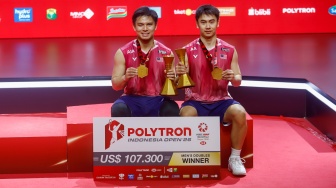 Pebulu tangkis ganda putra Malaysia Goh Sze Fei/Nur Izzuddin berpose dengan pialanya usai mengalahkan ganda putra Indonesia Raymond Indra/Nikolaus Joaquin pada final Polytron Indonesia Open 2026 di Istora Senayan, Jakarta, Minggu (7/6/2026). [Suara.com/Alfian Winanto]