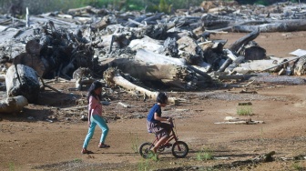 Anak-anak bermain sepeda di antara sisa material banjir bandang yang masih menutupi lapangan sepak bola Brandon di Lapai, Padang, Sumatera Barat, Rabu (10/6/2026). [ANTARA FOTO/Fitra Yogi/bar]
