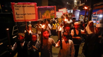 Sejumlah warga dan anak-anak mengikuti pawai obor di Kawasan Menteng, Jakarta Pusat, Senin (15/6/2026).  [Suara.com/Alfian Winanto]