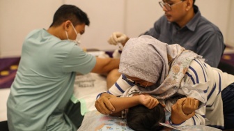 Orang tua memeluk anaknya saat proses sunat massal di Mal Kota Kasablanka, Jakarta, Selasa (16/6/2026). [Suara.com/Alfian Winanto]