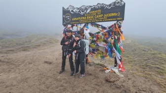 Pendaki berfoto di depan penanda Annapurna Base Camp (4.130 mdpl), Nepal, setelah menyelesaikan perjalanan trekking di kawasan Pegunungan Himalaya, Kamis (28/5/2026). [Suara.com/Rizka Chaerani] 