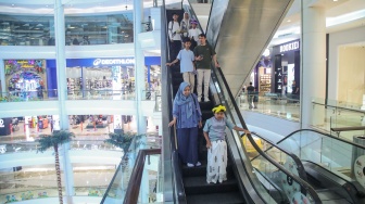 Orang tua bersama anaknya menuruni eskalator usai mengikuti proses sunat massal di Mal Kota Kasablanka, Jakarta, Selasa (16/6/2026). [Suara.com/Alfian Winanto]