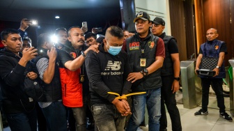 Petugas menggiring tersangka kasus dugaan penyekapan dan penganiayaan berat Taufik Hidayat (tengah) setibanya di Polda Jabar, Bandung, Jawa Barat, Selasa (23/6/2026). [ANTARA FOTO/Raisan Al Farisi/nym]