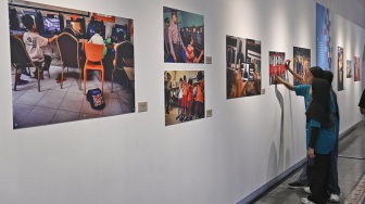 Pengunjung melihat karya foto saat pameran foto bertajuk Perisai Tunas di ANTARA Heritage Center, Jakarta, Kamis (25/6/2026). [Suara.com/Alfian Winanto]
