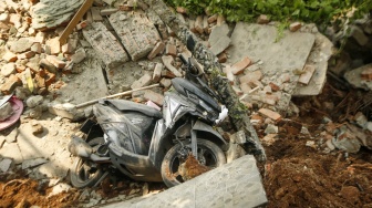 Sebuah sepeda motor berada di puing bangunan yang terdampak tanah longsor di Petamburan, Tanah Abang, Jakarta, Jumat (26/6/2026). [Suara.com/Alfian Winanto]