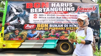 Warga membawa sayuran yang dibagikan massa aksi saat berunjuk rasa mendukung program MBG di Jakarta, Rabu (8/7/2026). [Suara.com/Alfian Winanto]