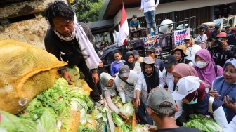 Massa aksi membagikan sayuran kepada warga saat berunjuk rasa mendukung program MBG di Jakarta, Rabu (8/7/2026). [Suara.com/Alfian Winanto]