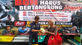 Massa aksi membagikan sayuran kepada warga saat berunjuk rasa mendukung program MBG di Jakarta, Rabu (8/7/2026). [Suara.com/Alfian Winanto]