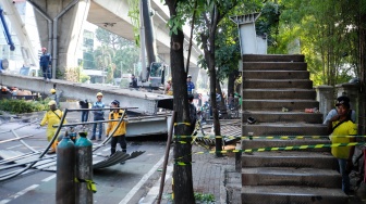 Petugas membongkar Jembatan Penyeberangan Orang (JPO) Tendean yang rusak usai tertabrak truk pengangkut alat berat di kawasan Tendean, Jakarta, Selasa (14/7/2026). [Suara.com/Alfian Winanto]