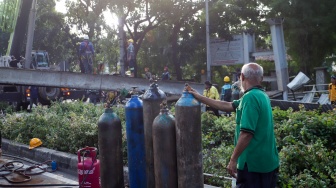 Petugas membongkar Jembatan Penyeberangan Orang (JPO) Tendean yang rusak usai tertabrak truk pengangkut alat berat di kawasan Tendean, Jakarta, Selasa (14/7/2026). [Suara.com/Alfian Winanto]