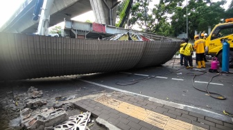 Petugas membongkar Jembatan Penyeberangan Orang (JPO) Tendean yang rusak usai tertabrak truk pengangkut alat berat di kawasan Tendean, Jakarta, Selasa (14/7/2026). [Suara.com/Alfian Winanto]